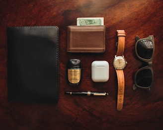 brown leather bifold wallet beside white apple airpods and white apple airpods