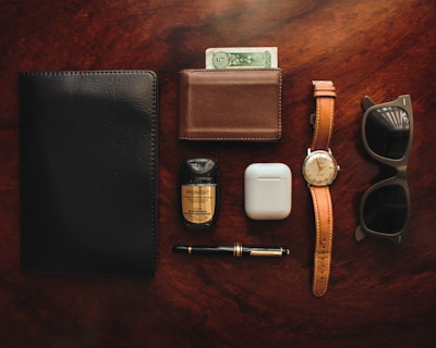 brown leather bifold wallet beside white apple airpods and white apple airpods