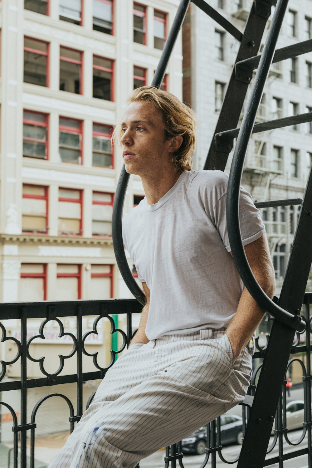 man in white crew neck t-shirt sitting on black metal railings