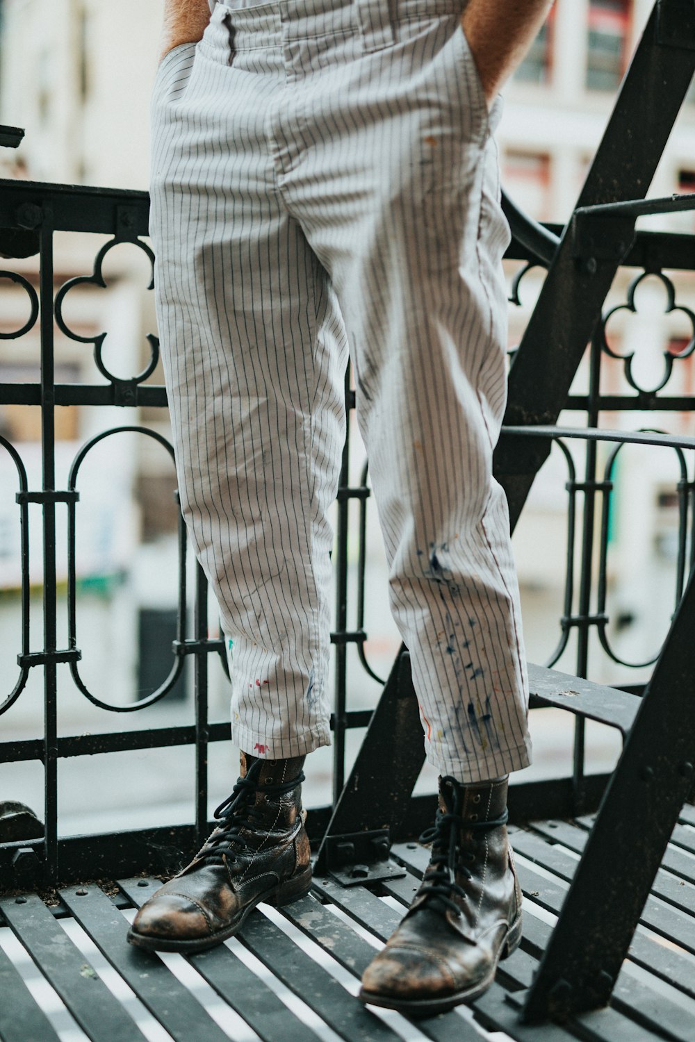 person in black leather shoes standing on black metal fence