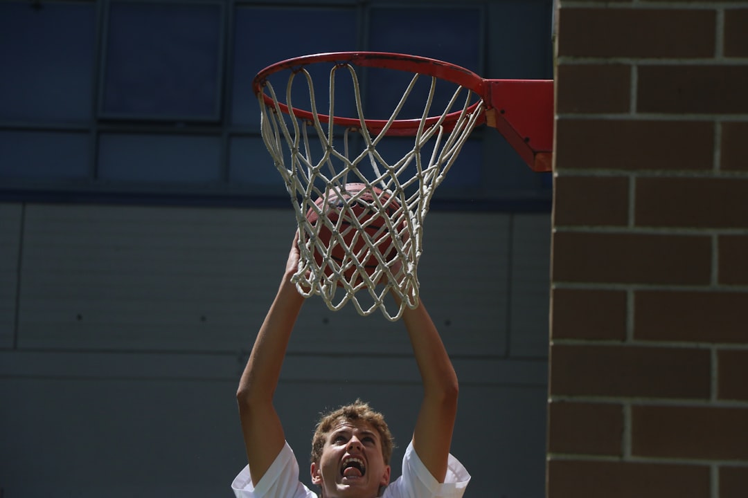 man in white t-shirt holding basketball hoop