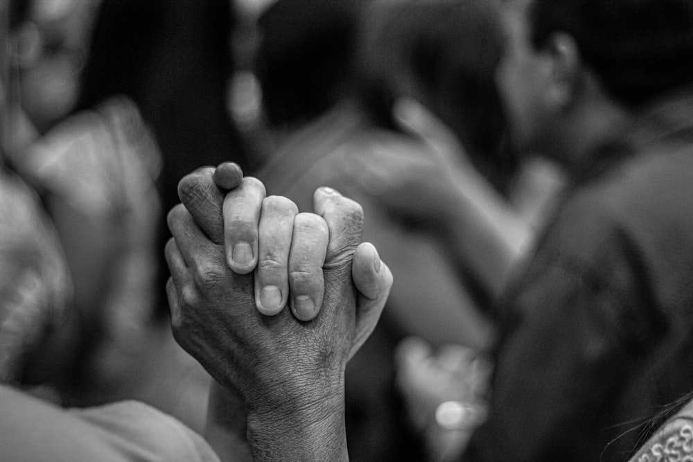 grayscale photo of people holding hands