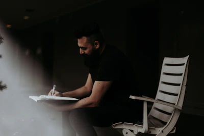 A thoughtful male therapist sitting comfortably with a notebook in hand.
