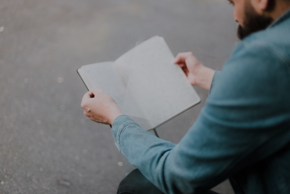 person in blue long sleeve shirt holding white paper