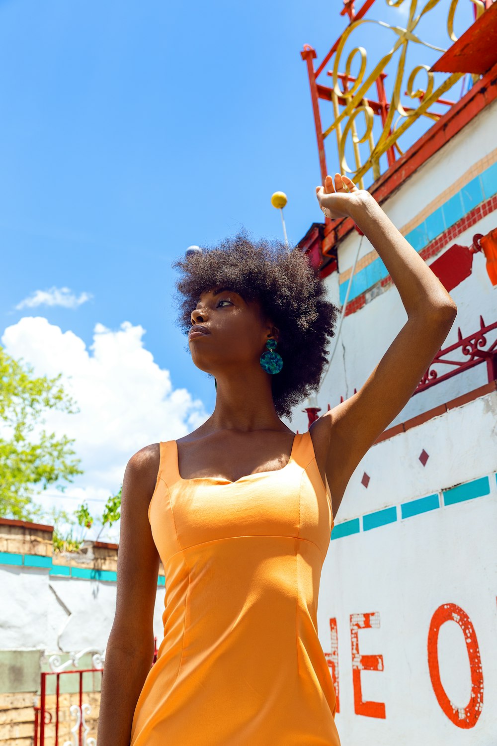 woman in yellow tank top standing near white and red wall during daytime