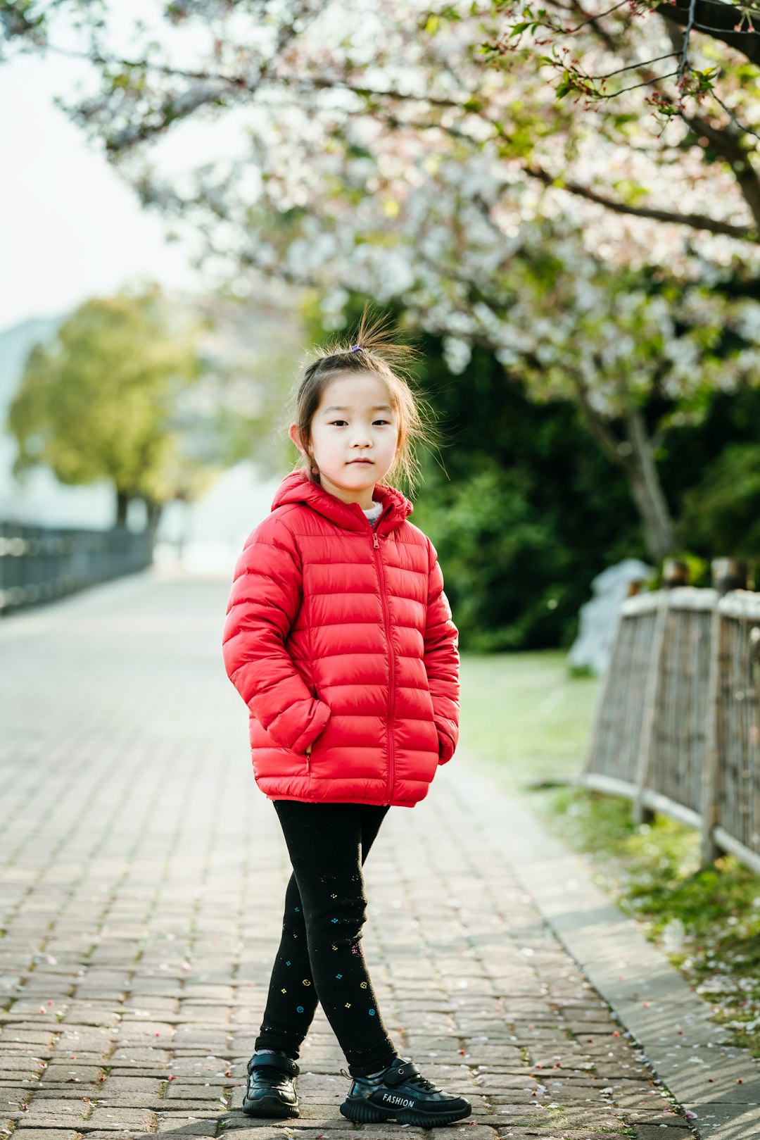 girl in red hoodie standing on gray concrete pathway during daytime