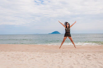 Mujer saltando feliz en la playa durante el día.