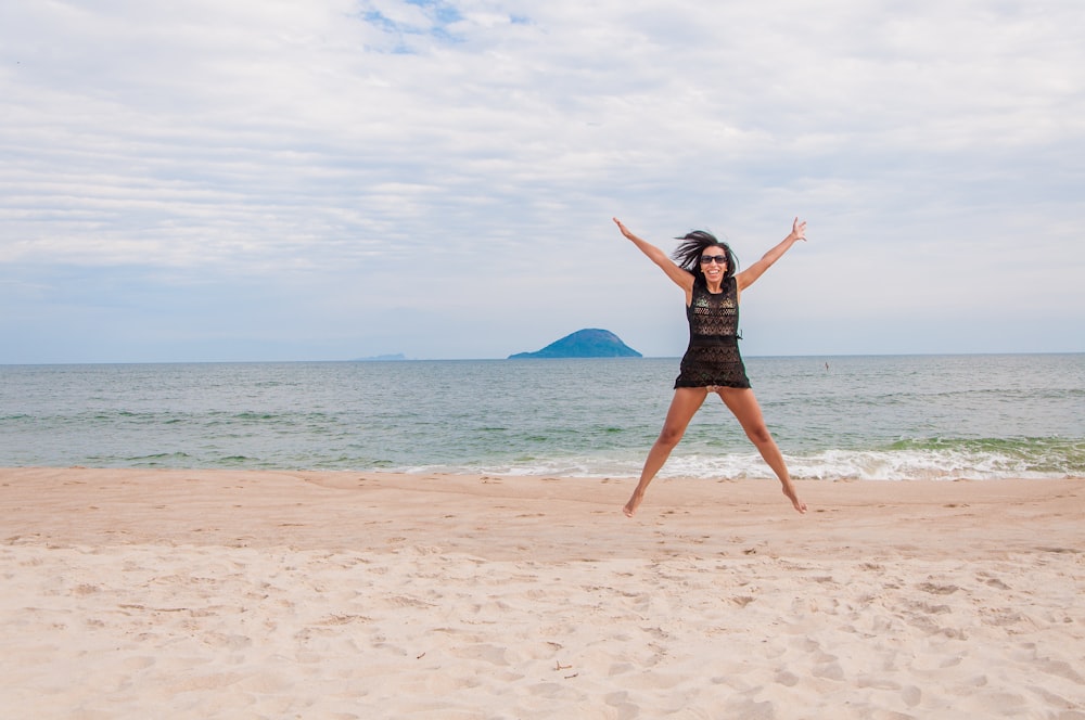 woman in black dress standing on beach during daytime