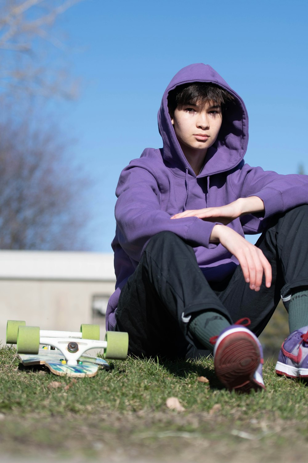 man in blue hoodie and blue denim jeans sitting on green grass field during daytime