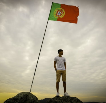 man in white t-shirt and brown shorts standing on rock