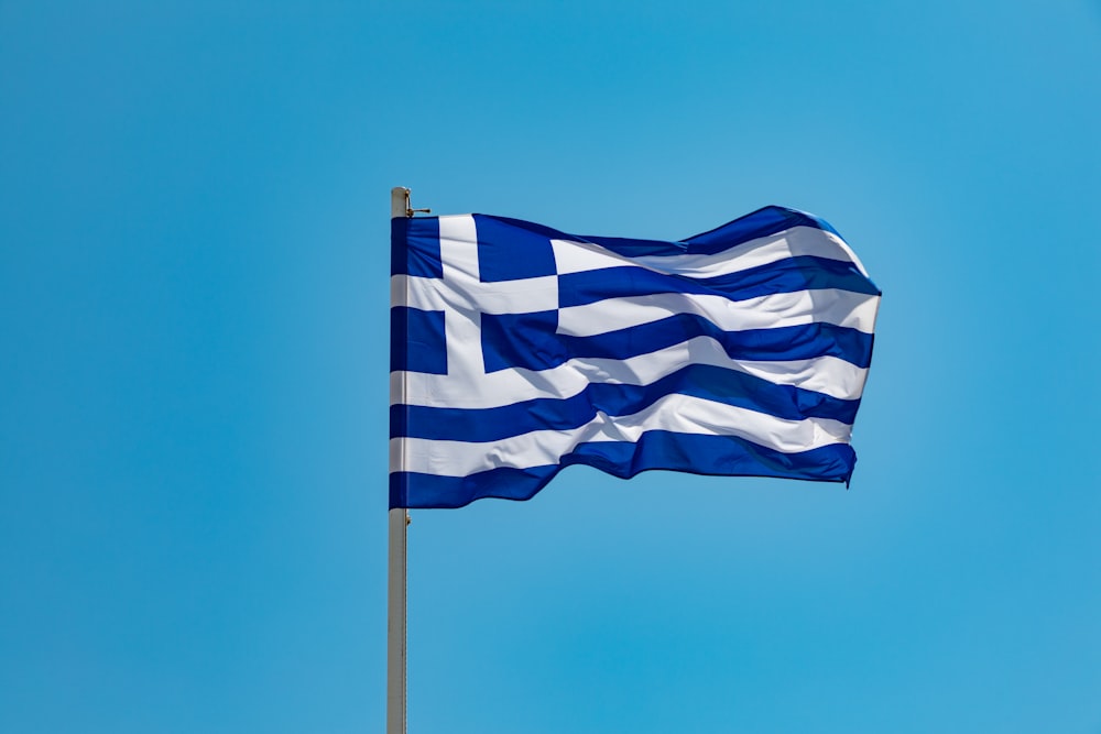 bandeira listrada azul e branca no mastro sob o céu azul durante o dia