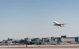 An airplane taking off with freight containers visible on the tarmac below.