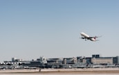 An airplane taking off with cargo containers visible in the background.