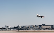 An airplane taking off with cargo containers visible on the tarmac below.