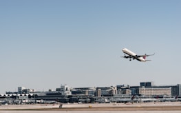 An airplane taking off with cargo containers visible in the background.