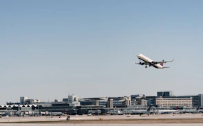 An airplane taking off with freight containers visible on the tarmac below.