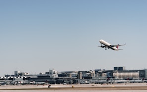 An airplane taking off with a backdrop of a sprawling logistics hub below.
