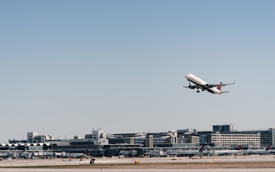 An airplane taking off with cargo containers visible on the tarmac below.