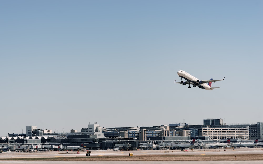 Weißes und schwarzes Flugzeug fliegt tagsüber über Stadtgebäude