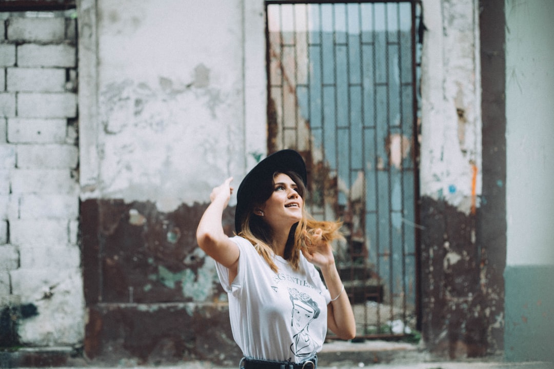 woman in white t-shirt and black knit cap standing near wall,