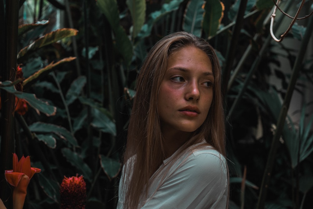 woman in white shirt standing near green plant during daytime