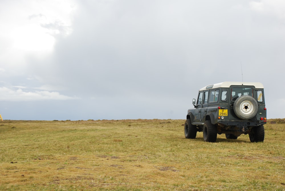 blue suv on brown field under white clouds during daytime