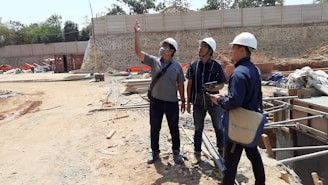 Three professionals reviewing construction plans at a busy heavy infrastructure site.
