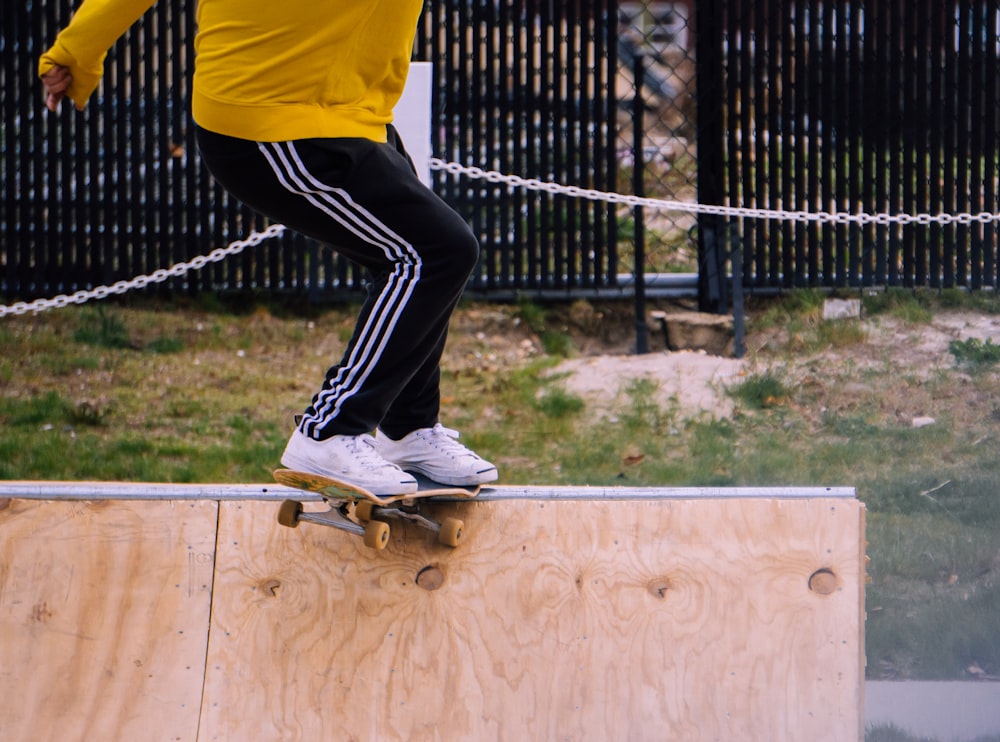 person in yellow shirt and black pants wearing white sneakers jumping on trampoline