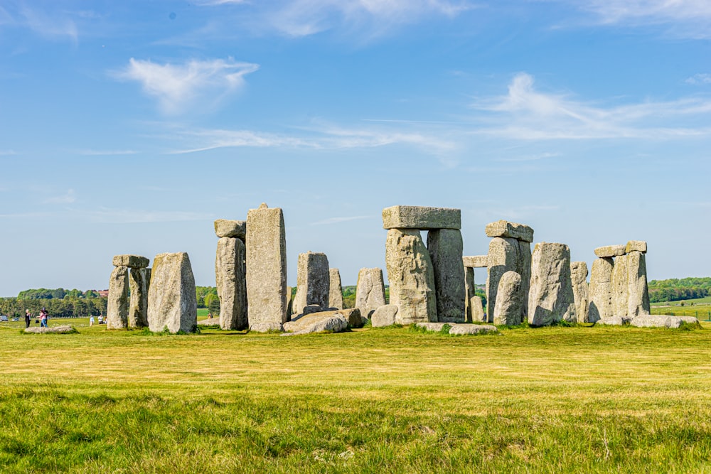 gray rock formation on green grass field under blue sky during daytime