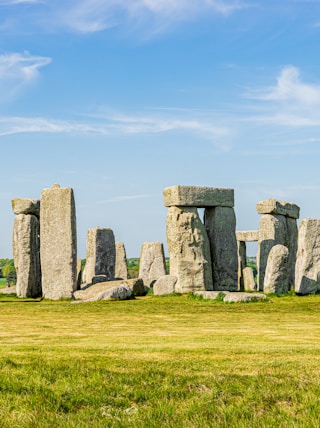 gray rock formation on green grass field under blue sky during daytime