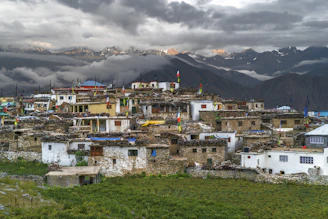 white and brown concrete houses near mountain under white clouds during daytime