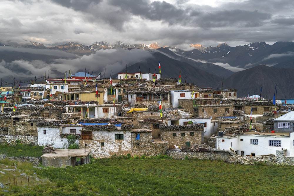 white and brown concrete houses near mountain under white clouds during daytime