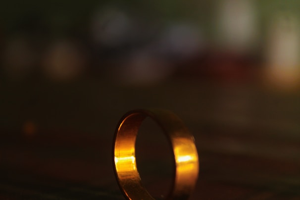 A sparkling gold ring catching the light against a soft, neutral background.