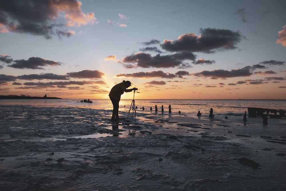 silhouette of man holding surfboard on beach during sunset