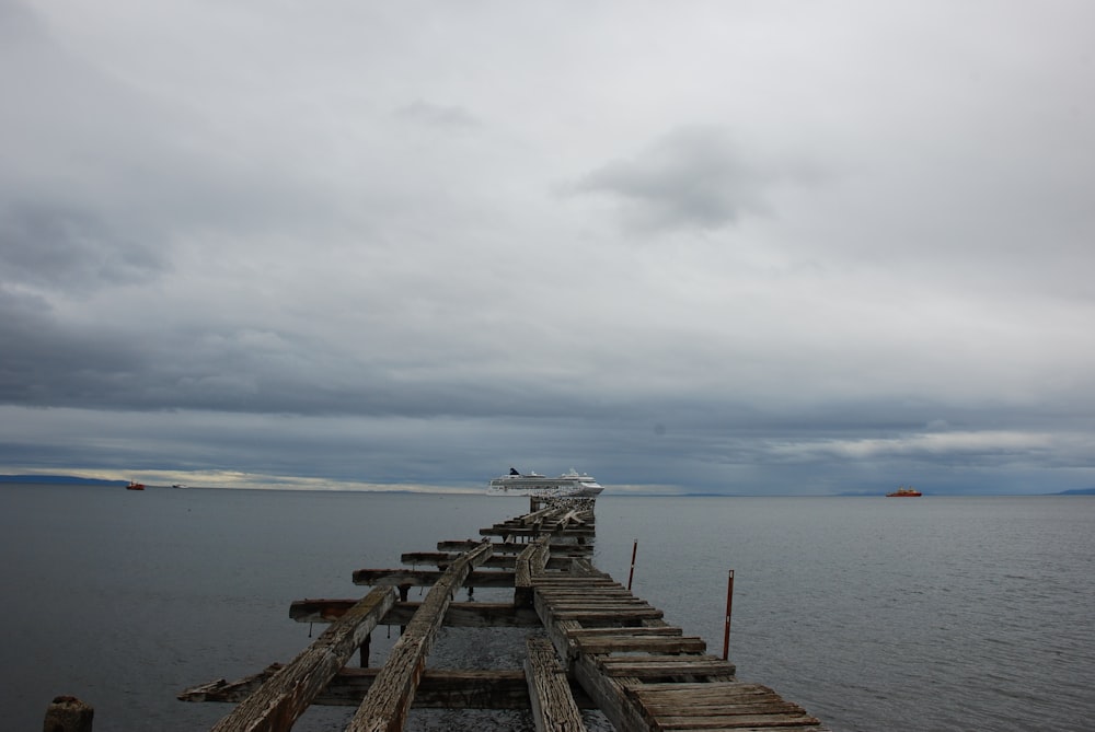 brown wooden dock on sea under white clouds during daytime