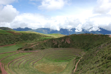 Lush green terraces of the Sacred Valley with mountains and rivers under a vibrant sky at sunset.