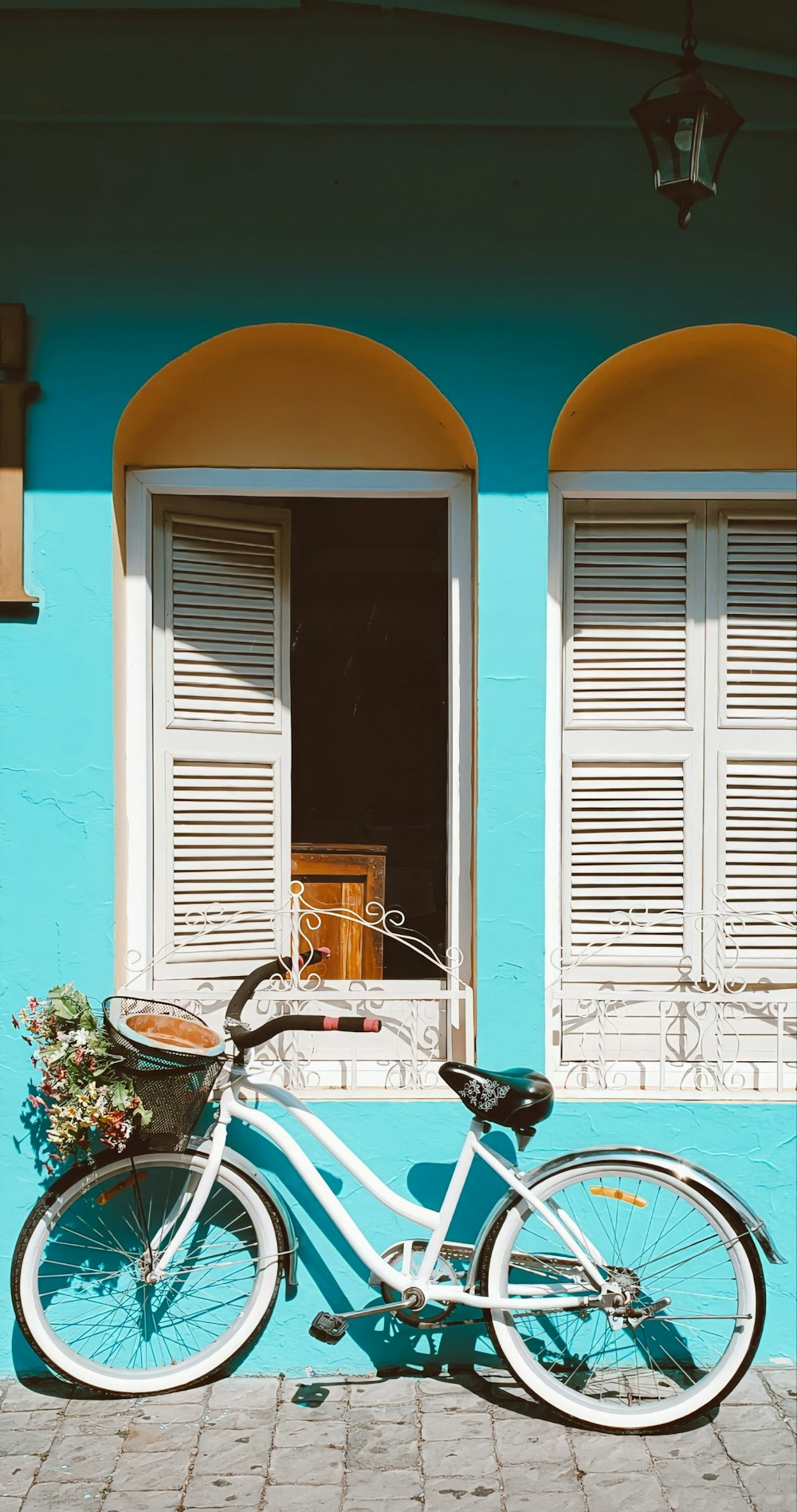 white and black bicycle parked beside white wooden window