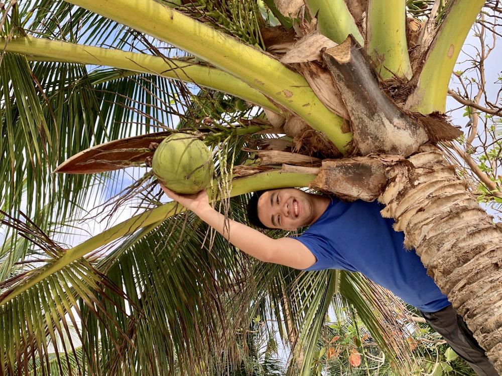 Mujer con camiseta azul de cuello redondo sosteniendo la fruta del coco