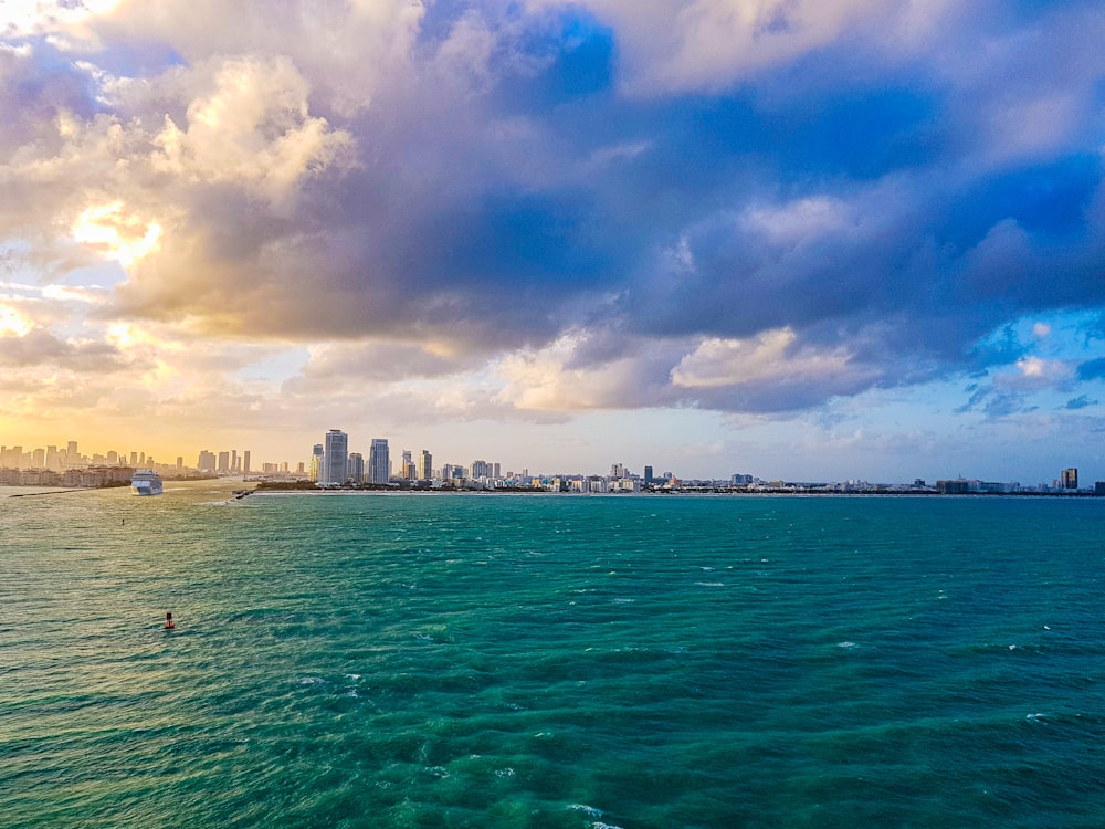 city skyline across body of water under blue and white sunny cloudy sky during daytime