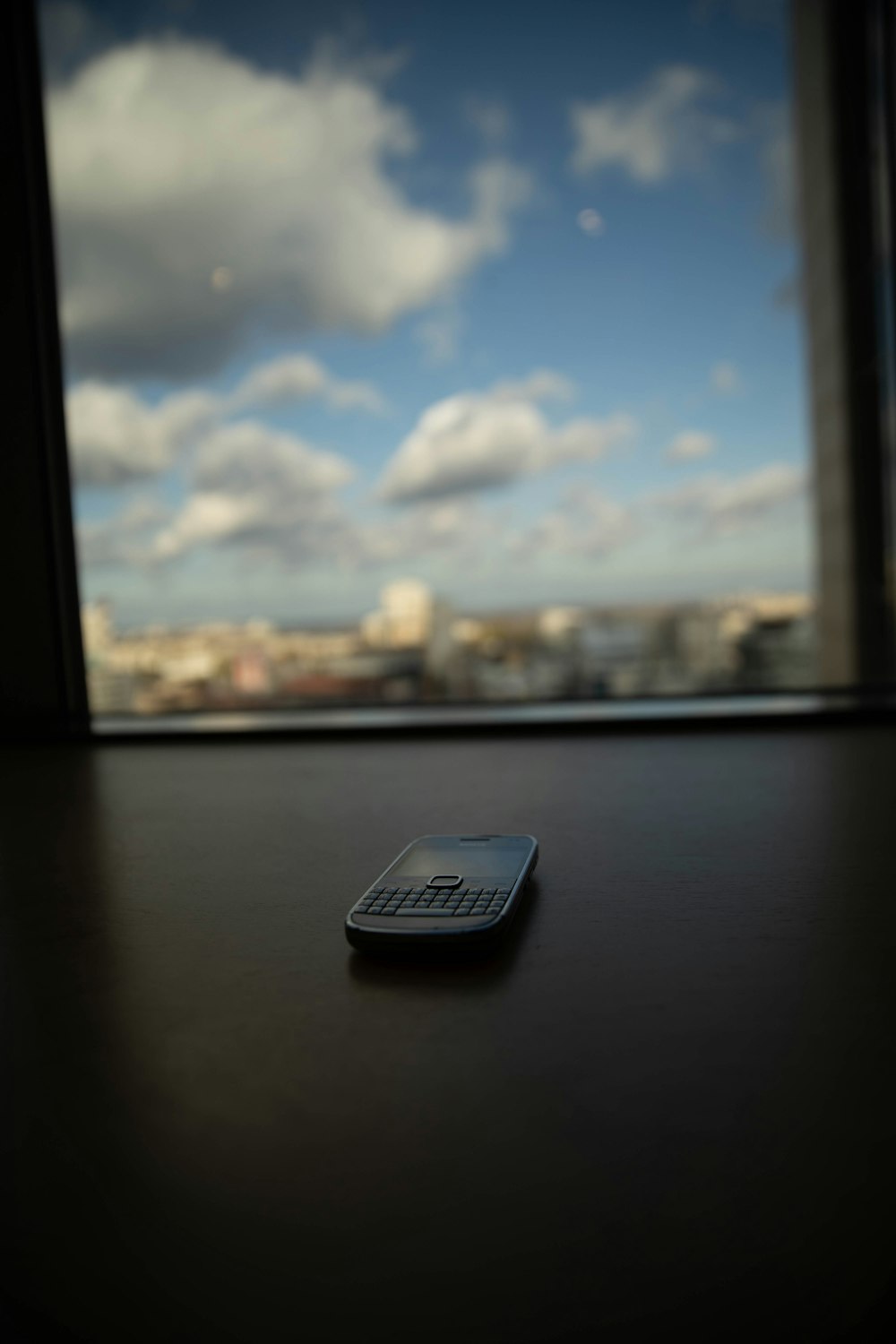 Schwarz-Weiß-QWERTY-Telefon auf braunem Holztisch