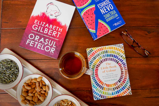 A rustic wooden table with open guidebooks and a cup of herbal tea, surrounded by pine branches.