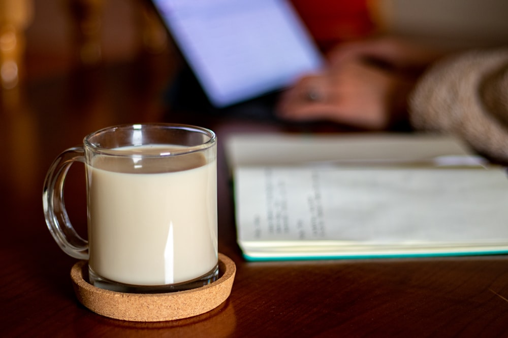 clear drinking glass with white liquid on brown wooden table