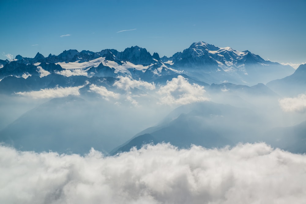 snow covered mountains under white clouds during daytime