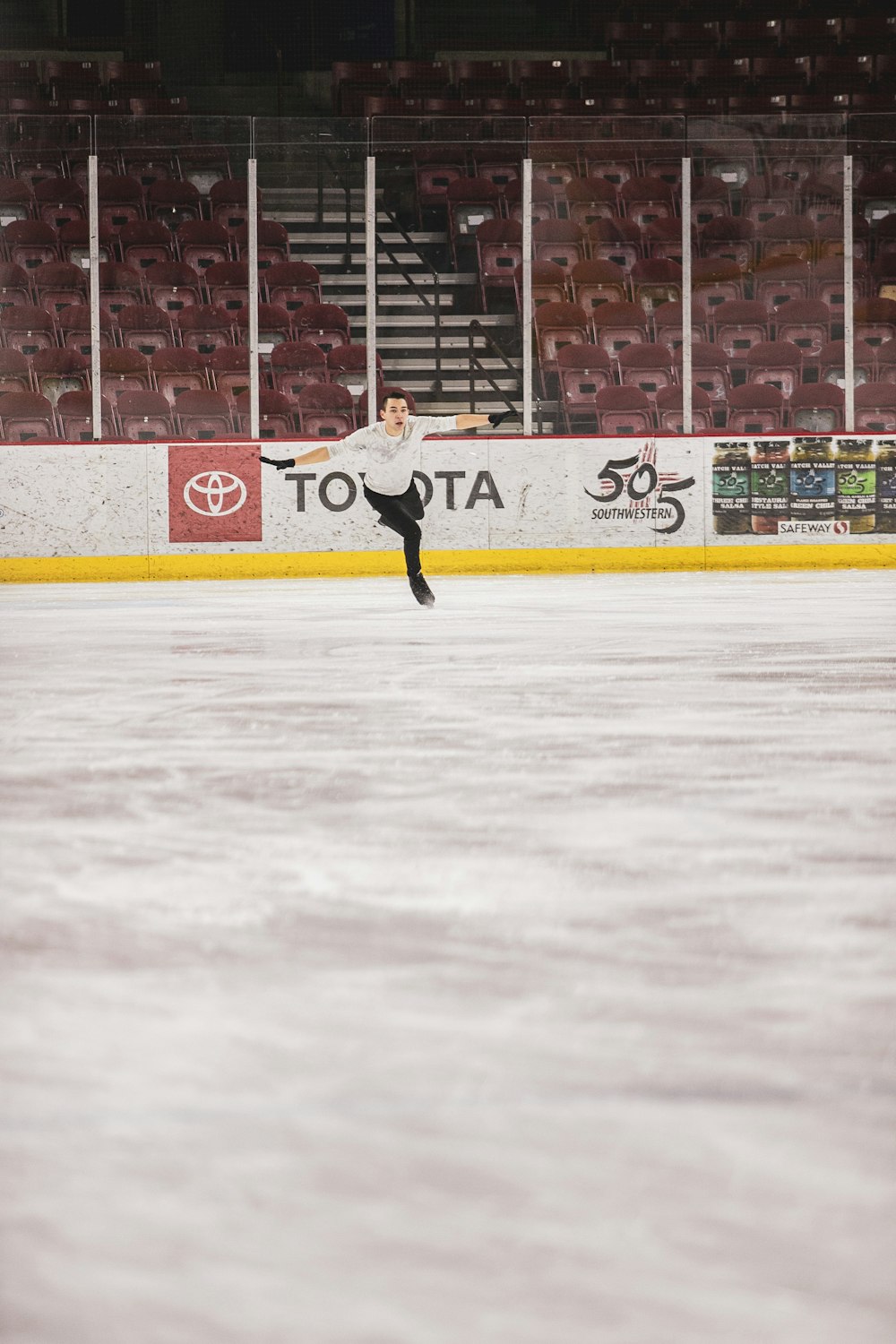 man in white shirt and black pants playing ice hockey