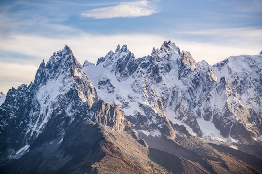 brown and white mountain under white clouds during daytime in Mer de Glace France