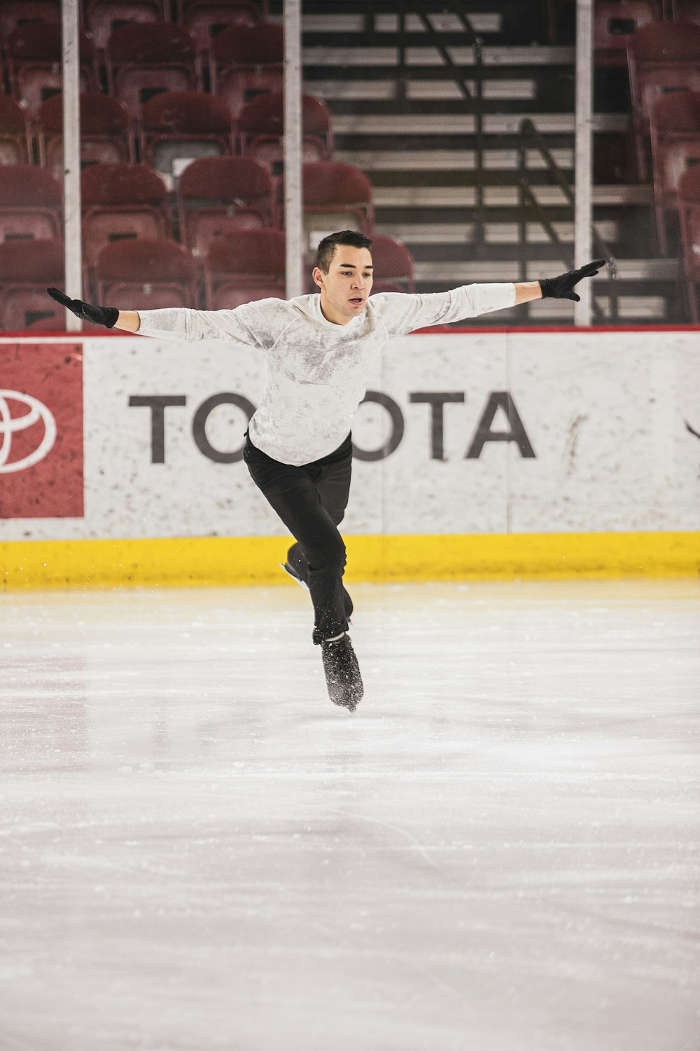 woman in white long sleeve shirt and black pants standing on ice hockey field