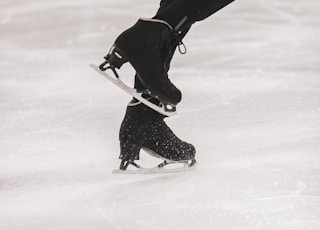 person in black jacket and black pants playing ice hockey