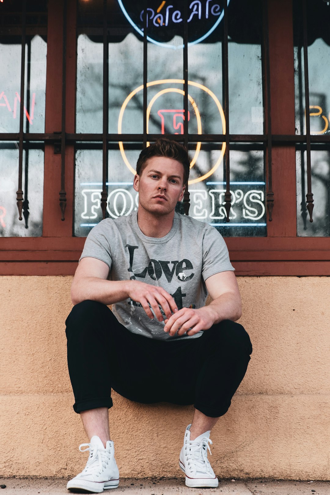 man in gray crew neck t-shirt and black pants sitting on brown concrete floor