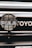 A close-up view of a car's front grill featuring a PIAA auxiliary light with a protective grid and branding, and part of the Toyota emblem visible in the background.