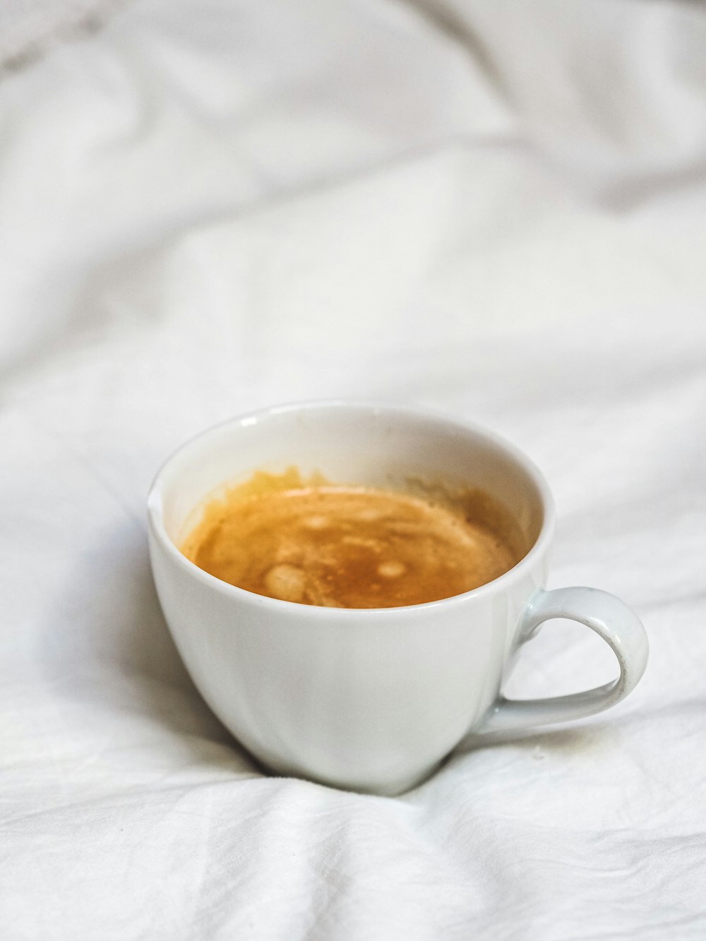 white ceramic mug on white textile